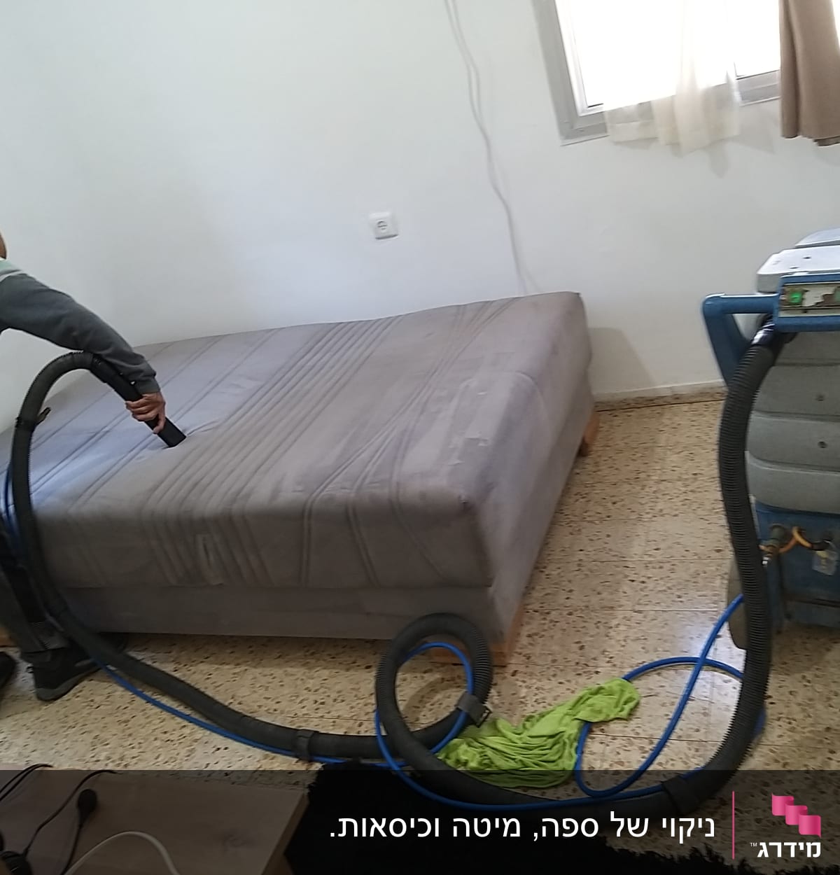 אדם מנקה מזרן עם שואב אבק תעשייתי